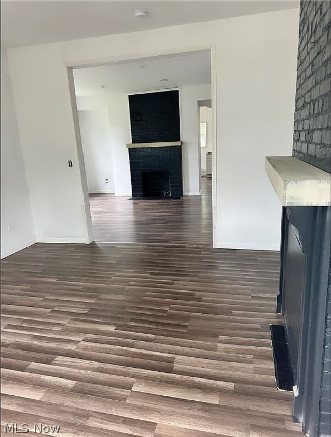 Unfurnished living room featuring dark hardwood / wood-style floors and a large fireplace | Image 4