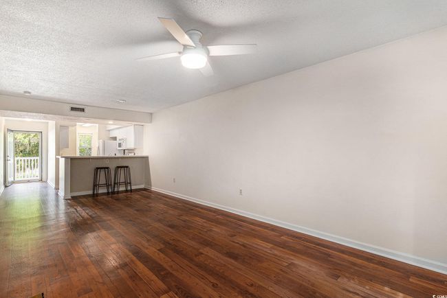 Unfurnished living room featuring baseboards, dark wood finished floors, a ceiling fan, and a textured ceiling | Image 26