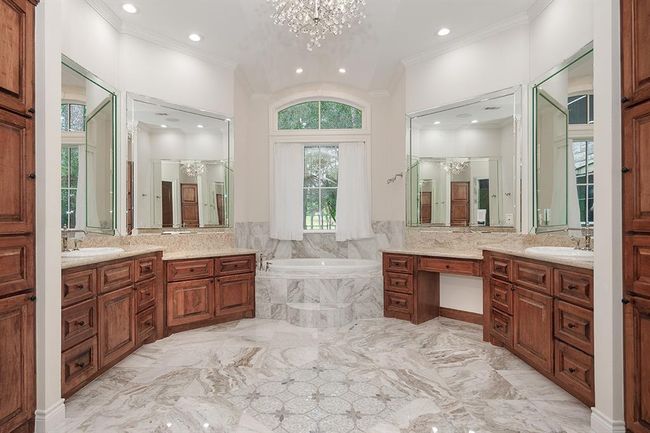 Luxurious bath with soaking tub, dual sinks, vanity area and decorative inlay centered on the tile floor | Image 21