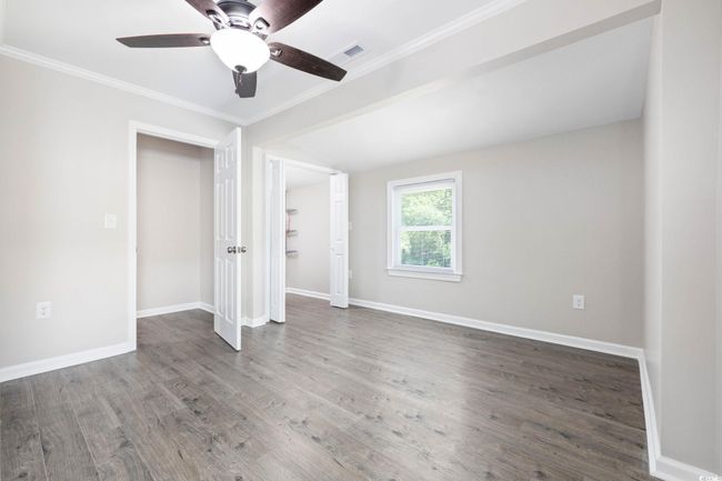 Unfurnished bedroom with wood finished floors, baseboards, crown molding, and a ceiling fan | Image 16