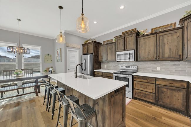 Kitchen with tasteful backsplash, crown molding, a breakfast bar area, appliances with stainless steel finishes, and a sink | Image 13