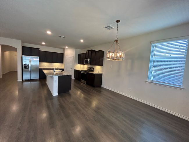 Kitchen with stainless steel appliances, a sink, a chandelier, arched walkways, and baseboards | Image 7