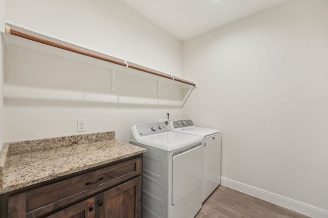 Laundry room featuring light wood-plant Tile floor, baseboards, washer and dryer, and laundry area | Image 32