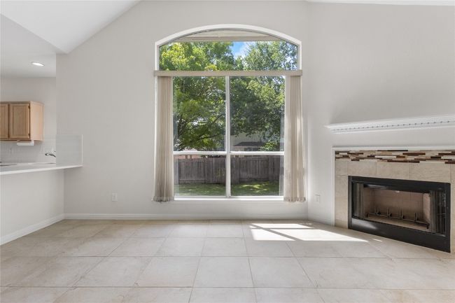 Unfurnished living room with light tile patterned floors, a fireplace, lofted ceiling, and recessed lighting | Image 25