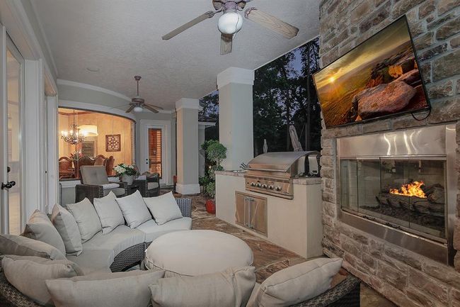 Stylish outdoor living and dining area with cozy fireplace and TV mounting | Image 37