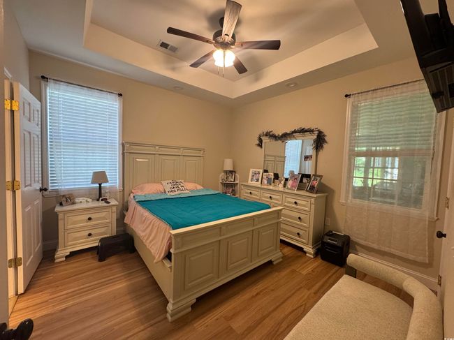 Bedroom featuring a raised ceiling, light wood finished floors, and ceiling fan | Image 14