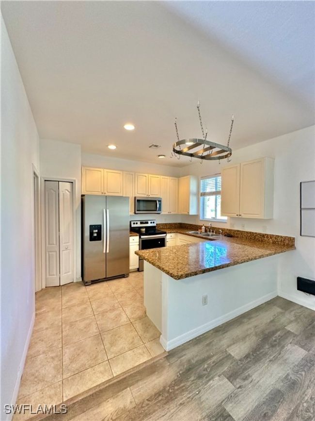 Kitchen with sink, dark stone countertops, light hardwood / wood-style floors, kitchen peninsula, and stainless steel appliances | Image 8
