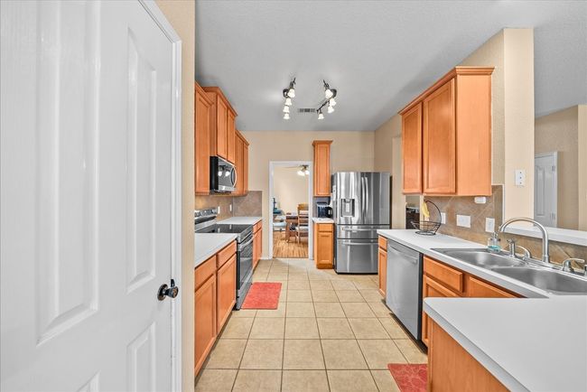 Kitchen with stainless steel appliances, a sink, tasteful backsplash, light tile patterned flooring, and a ceiling fan | Image 23
