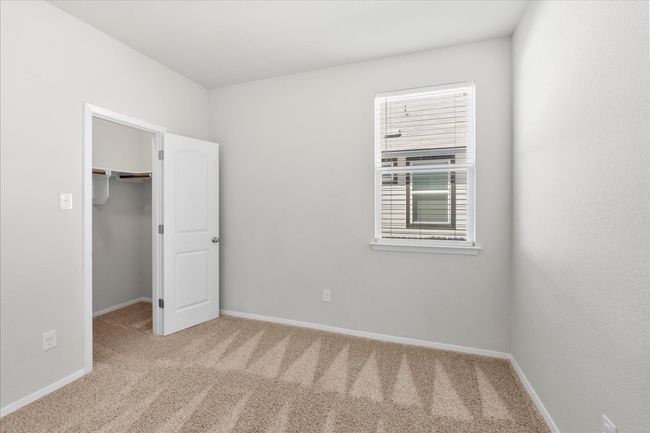 Unfurnished bedroom featuring a closet, a walk in closet, carpet flooring, and baseboards | Image 24