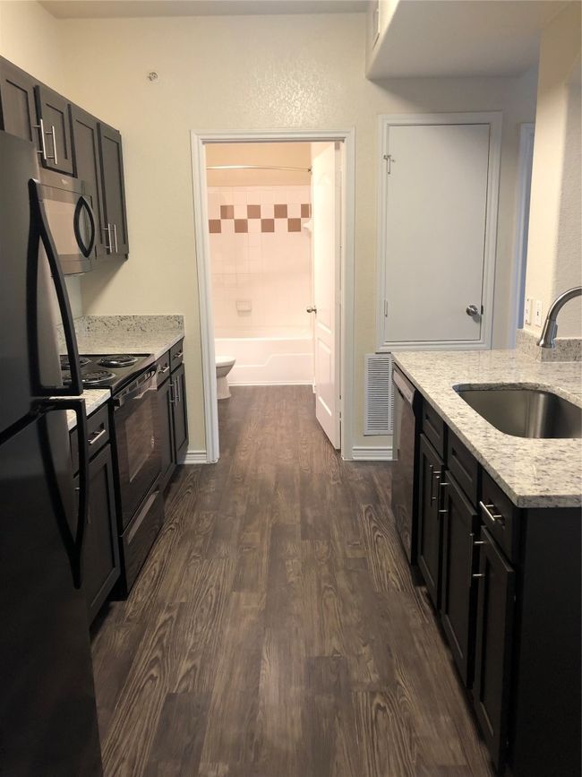 Kitchen with dishwasher, a sink, dark wood finished floors, fridge, and stove | Image 6