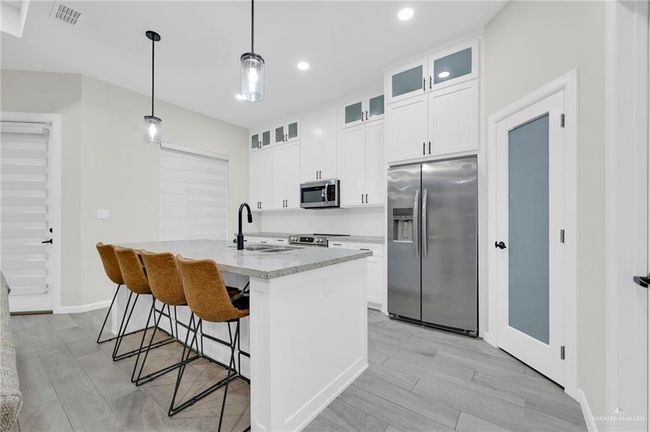 Kitchen with light wood-style tile flooring, a sink, appliances with stainless steel finishes, and visible vents | Image 11