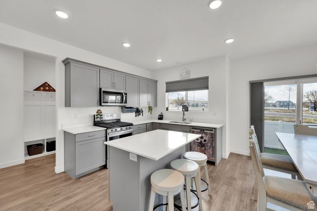 Kitchen with gray cabinetry, beverage cooler, a sink, and appliances with stainless steel finishes | Image 6