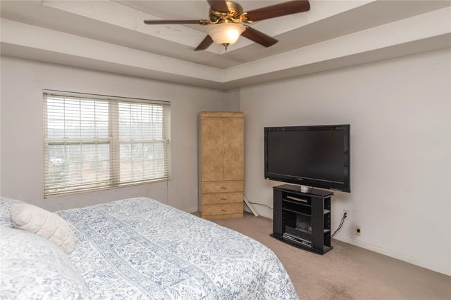 Carpeted bedroom featuring a raised ceiling, a ceiling fan, and baseboards | Image 28