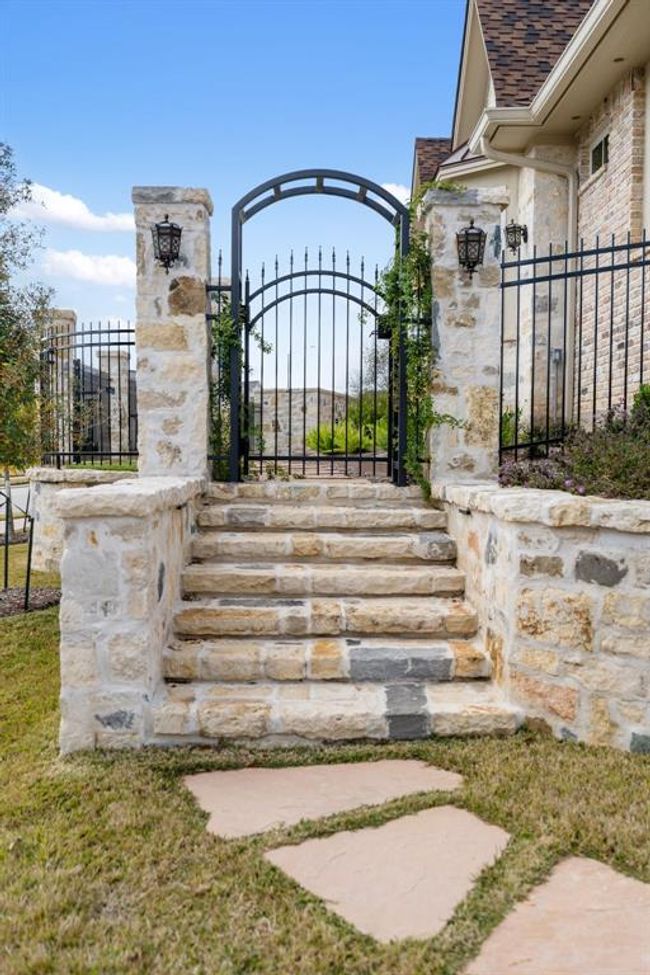The entranceon the side yard is abeautiful arched irongate and custom blend natural stonegarden/bed walls. | Image 46