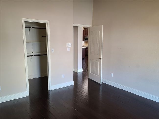 Unfurnished bedroom with dark wood-type flooring, a towering ceiling, and a closet | Image 19
