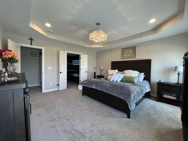 Owners Suite- tray ceiling with chandelier, walk in shower with stone flooring upgraded tile surround, dual vanity, WC, soaker tub | Image 25