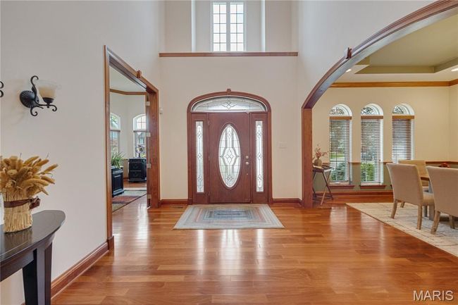 Foyer with arched walkways, healthy amount of natural light, wood finished floors, and a towering ceiling | Image 7