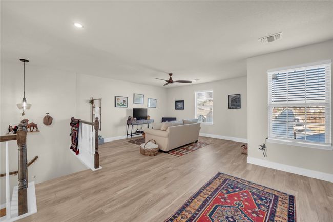 Loft space currently being used as a Living area featuring wood finished floors, recessed lighting, baseboards, and ceiling fan | Image 15