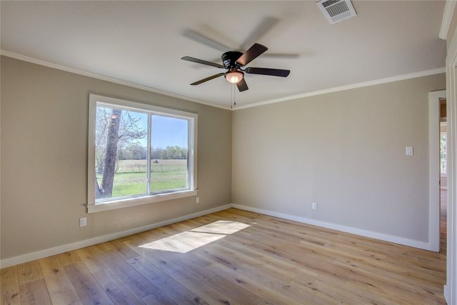 Spare room featuring visible vents, baseboards, ceiling fan, crown molding, and hardwood / wood-style flooring | Image 12