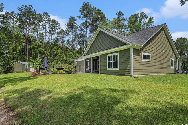 Rear view of property featuring an outbuilding, a yard, a storage shed, and roof with shingles | Image 34