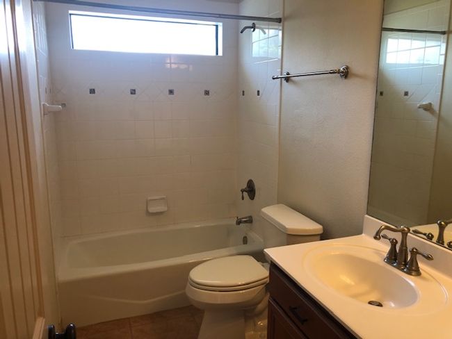 Full bathroom featuring vanity, toilet, tile patterned floors, and washtub / shower combination | Image 11