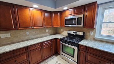 Kitchen with sink, light stone counters, appliances with stainless steel finishes, a kitchen bar, and a center island | Image 3