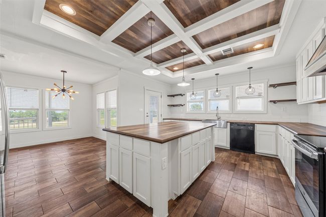 Kitchen with open shelves, butcher block countertops, decorative light fixtures, coffered ceiling, and ornamental molding | Image 11