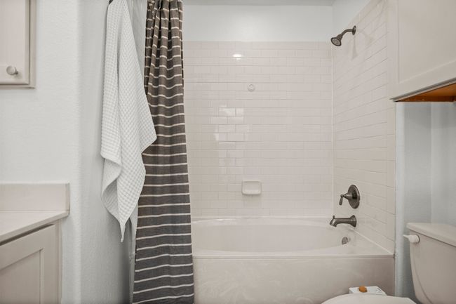 Bathroom featuring toilet, shower / bath combination with curtain, and vanity | Image 16