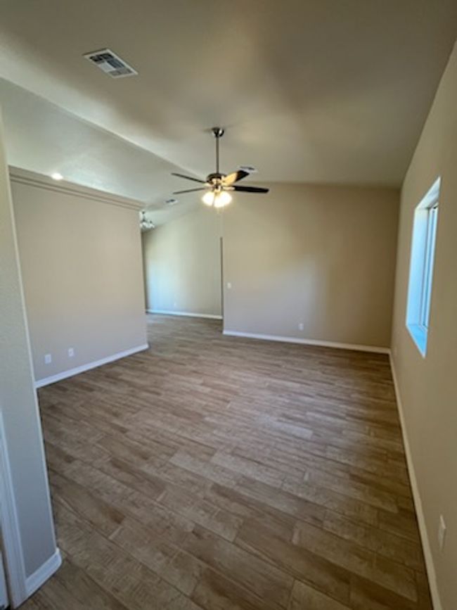 Spare room with baseboards, wood finished floors, a ceiling fan, and vaulted ceiling | Image 11