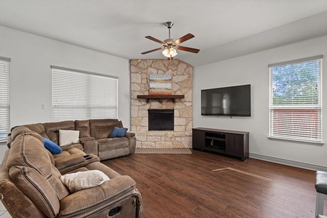 Living area featuring a ceiling fan, dark wood-type flooring, and a fireplace | Image 10