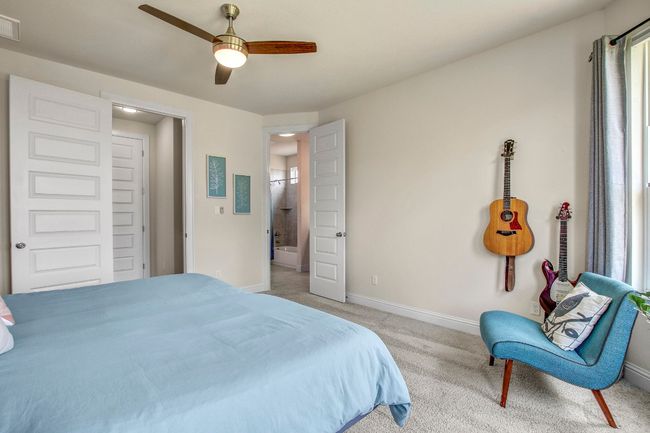 Bedroom with light colored carpet, multiple windows, a ceiling fan, and connected bathroom | Image 17