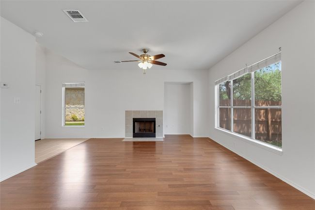 Unfurnished living room with ceiling fan, wood finished floors, and a tiled fireplace | Image 5
