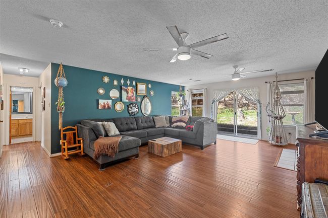 Living area featuring wood-type flooring, a textured ceiling, and ceiling fan | Image 9