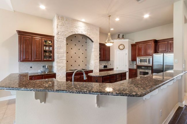 Kitchen featuring stainless steel appliances, a breakfast bar, tasteful backsplash, a large island, and recessed lighting | Image 15