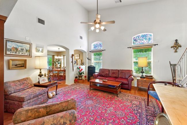 Living room Vinyl floors, a ceiling fan, arched walkways, stairs, and a chandelier | Image 5