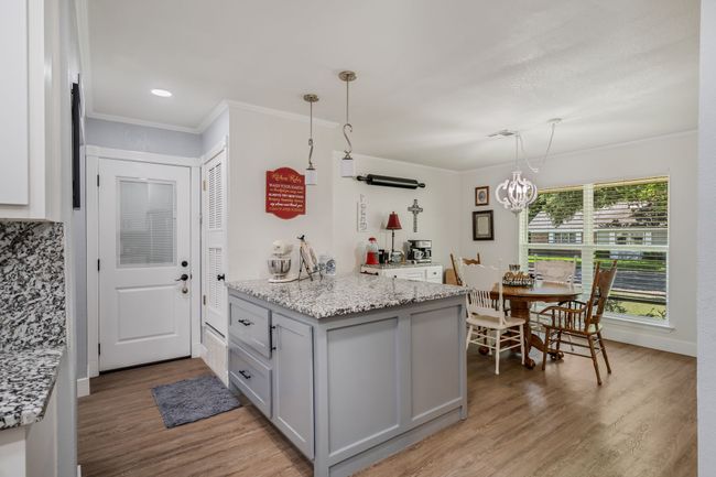 Kitchen featuring a peninsula, light wood-type flooring, ornamental molding, a chandelier, and pendant lighting | Image 11