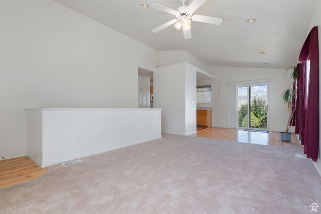 Unfurnished living room featuring vaulted ceiling, light colored carpet, a ceiling fan, and recessed lighting | Image 4