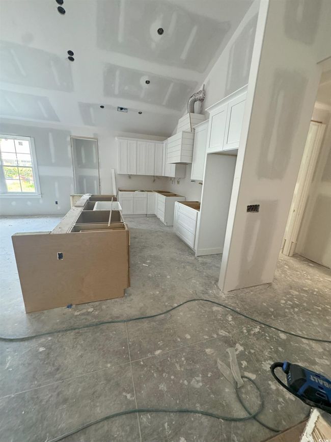 Kitchen with white cabinetry, lofted ceiling, and a kitchen island | Image 36