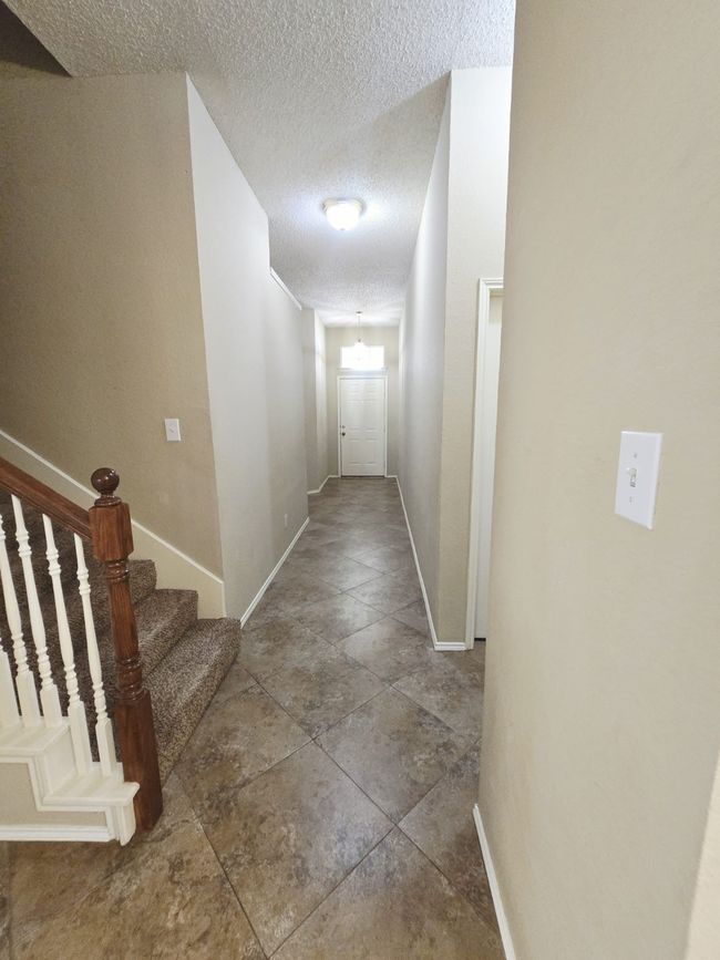Corridor featuring baseboards, a textured ceiling, and stairway | Image 6