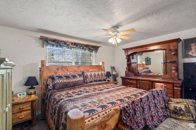 Bedroom with a textured ceiling, ceiling fan, and wood finished floors | Image 12