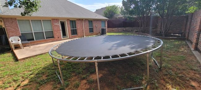 Fenced backyard with a trampoline and a patio area | Image 13
