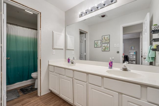 Full bath with double vanity, wood finished floors, toilet, and curtained shower | Image 10