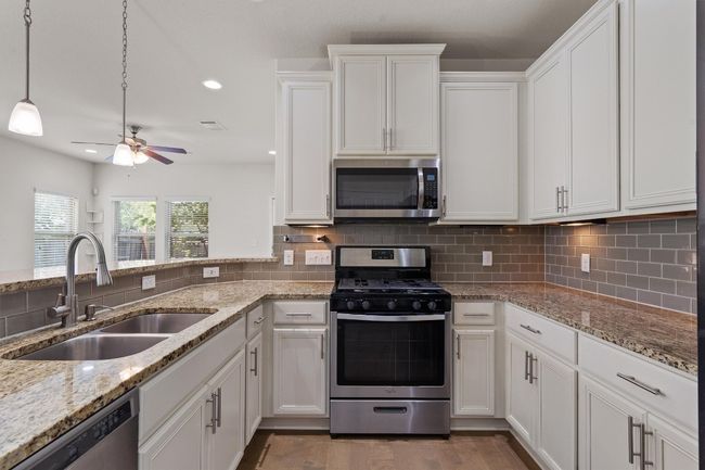 Kitchen with appliances with stainless steel finishes, a sink, white cabinetry, backsplash, and recessed lighting | Image 12
