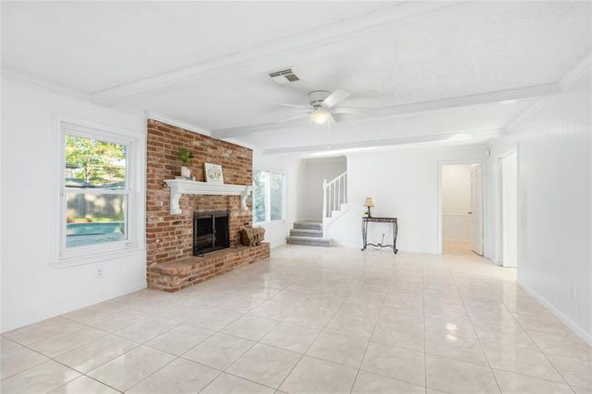 Another view of the living area looking at the stairs and door that leads into an office, studio, or extra bedroom. | Image 13