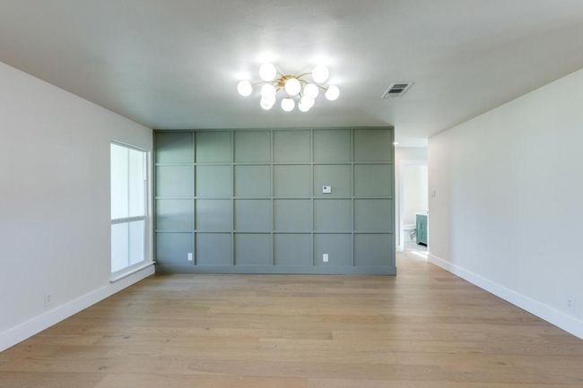Empty room featuring baseboards, light wood finished floors, visible vents, and an inviting chandelier | Image 12
