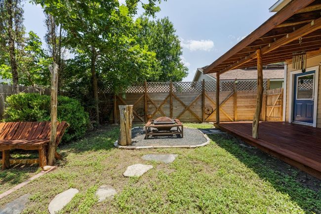 View of yard featuring a fire pit, a wooden deck and seating. | Image 26