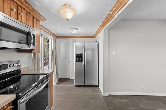 Kitchen featuring baseboards, light countertops, brown cabinetry, and appliances with stainless steel finishes | Image 12