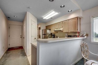 Kitchen featuring light carpet, a textured ceiling, light brown cabinetry, and stainless steel refrigerator | Image 3