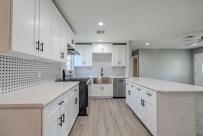 Bright and modern kitchen with sleek and inviting design. The space features expansive countertops and an oversized island that offer ample workspace and seating options. | Image 7
