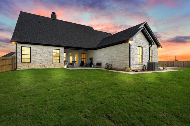 Back of property featuring stone siding, a chimney, a patio, and a shingled roof | Image 35